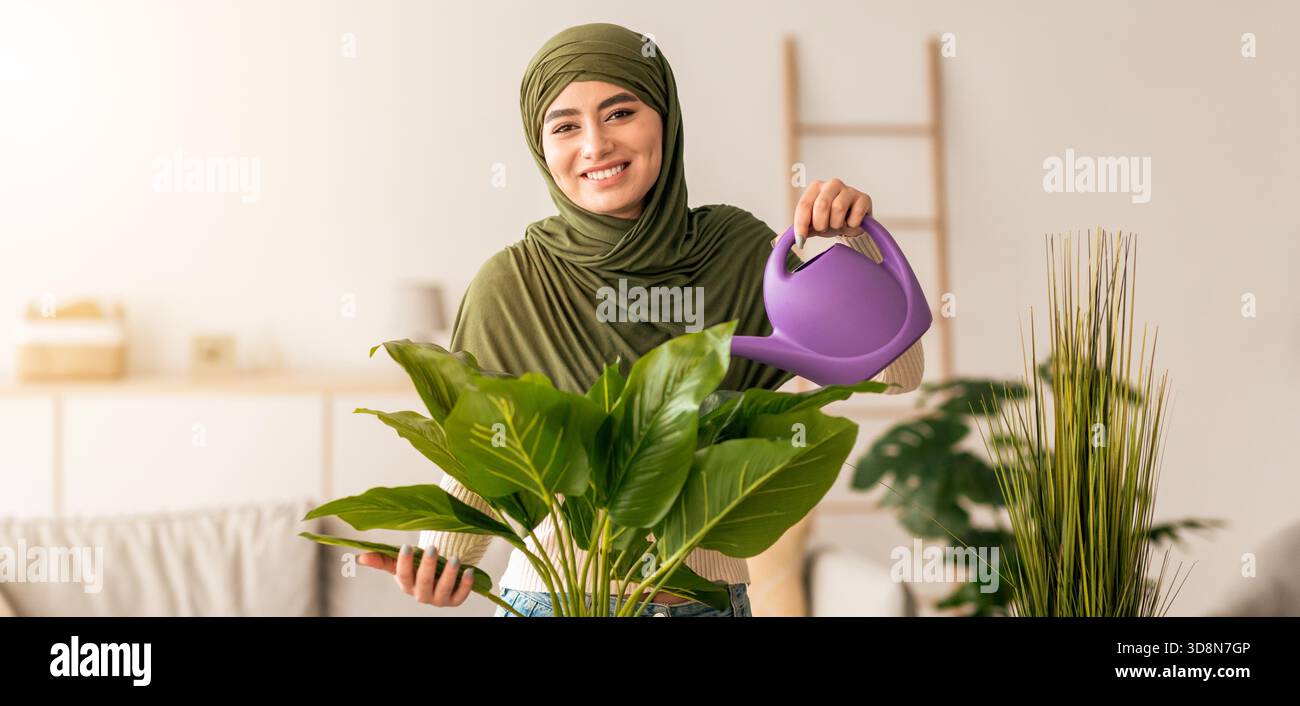 Frau in grünem Kopftuch bewässert Indoor Pflanzen in gemütlichem Wohnzimmer gefüllt mit Grün Stockfoto