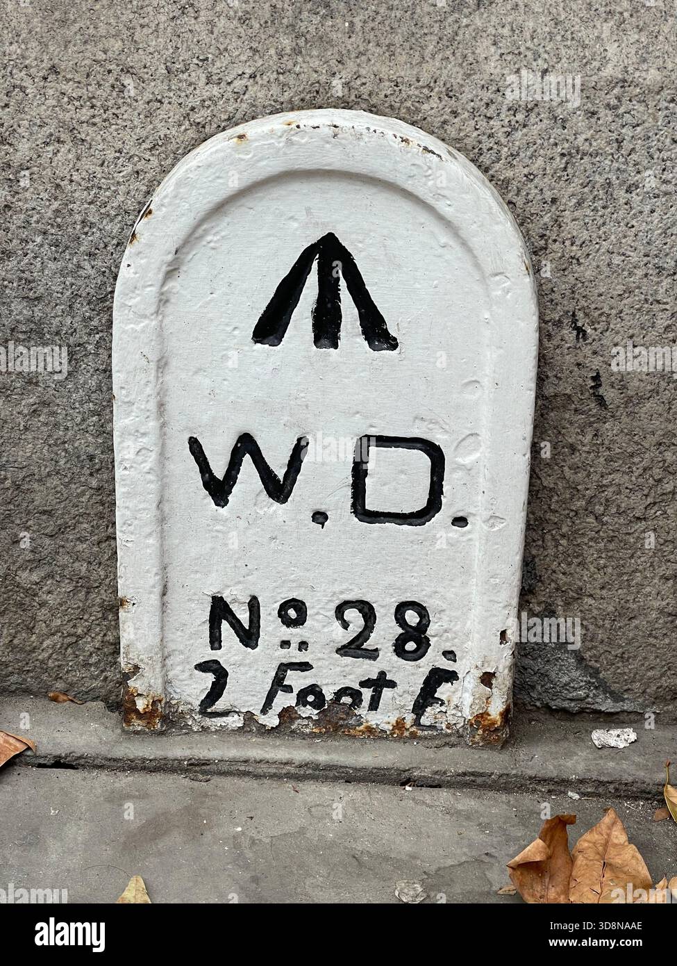 Grenzmarkierung des Kriegsministeriums Nr. 28 mit breitem Pfeilsymbol, die einen historischen Vermessungspunkt St Katharine's Way in London, Großbritannien, angibt. Stockfoto