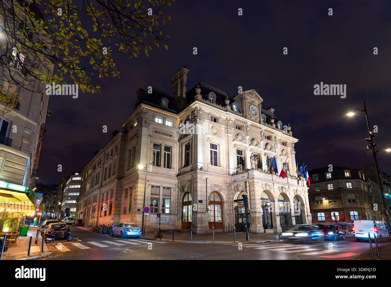 Rathaus des 18. Arrondissements in Paris, Frankreich. Das historische Gebäude mit Uhrenturm und Fahnen steht nachts am Place Jules Joffrin Stockfoto