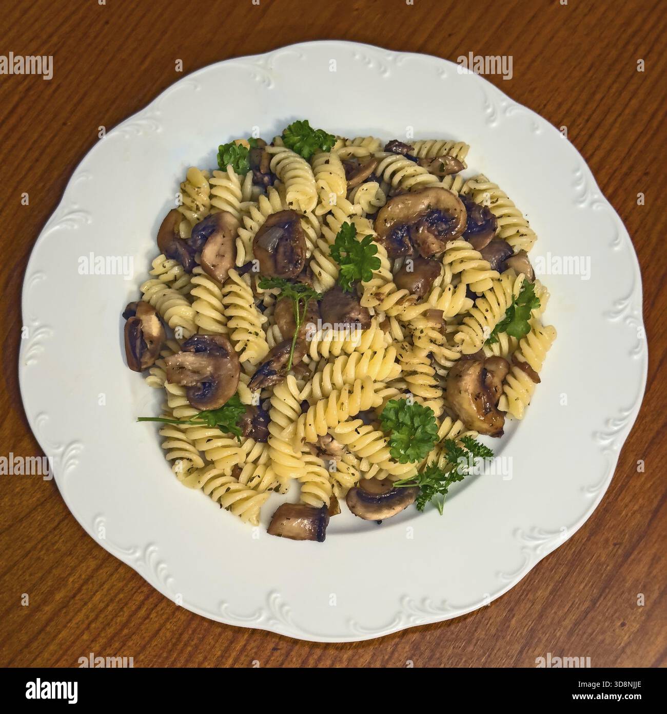 Einfaches italienisches Gericht Pasta Fusilli mit Pilzen garniert mit Petersilie, vegane Küche, internationale Küche Stockfoto