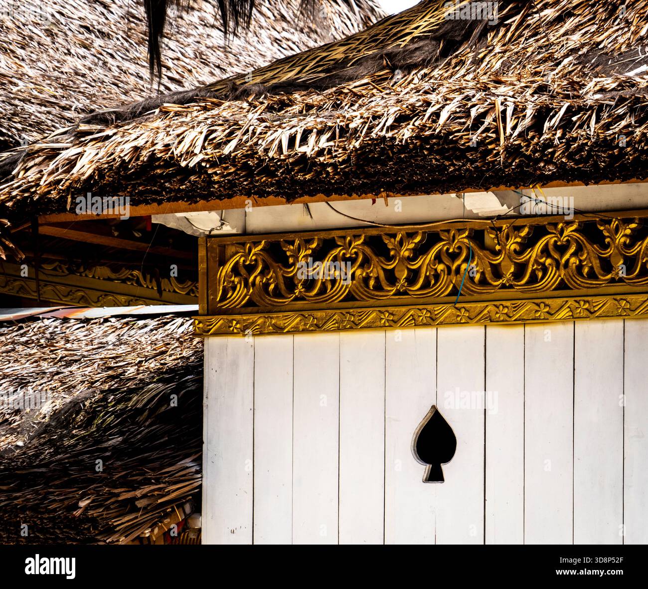 Traditionelles Gebäude mit kunstvollen goldenen Zierleisten und Strohdach. Stockfoto