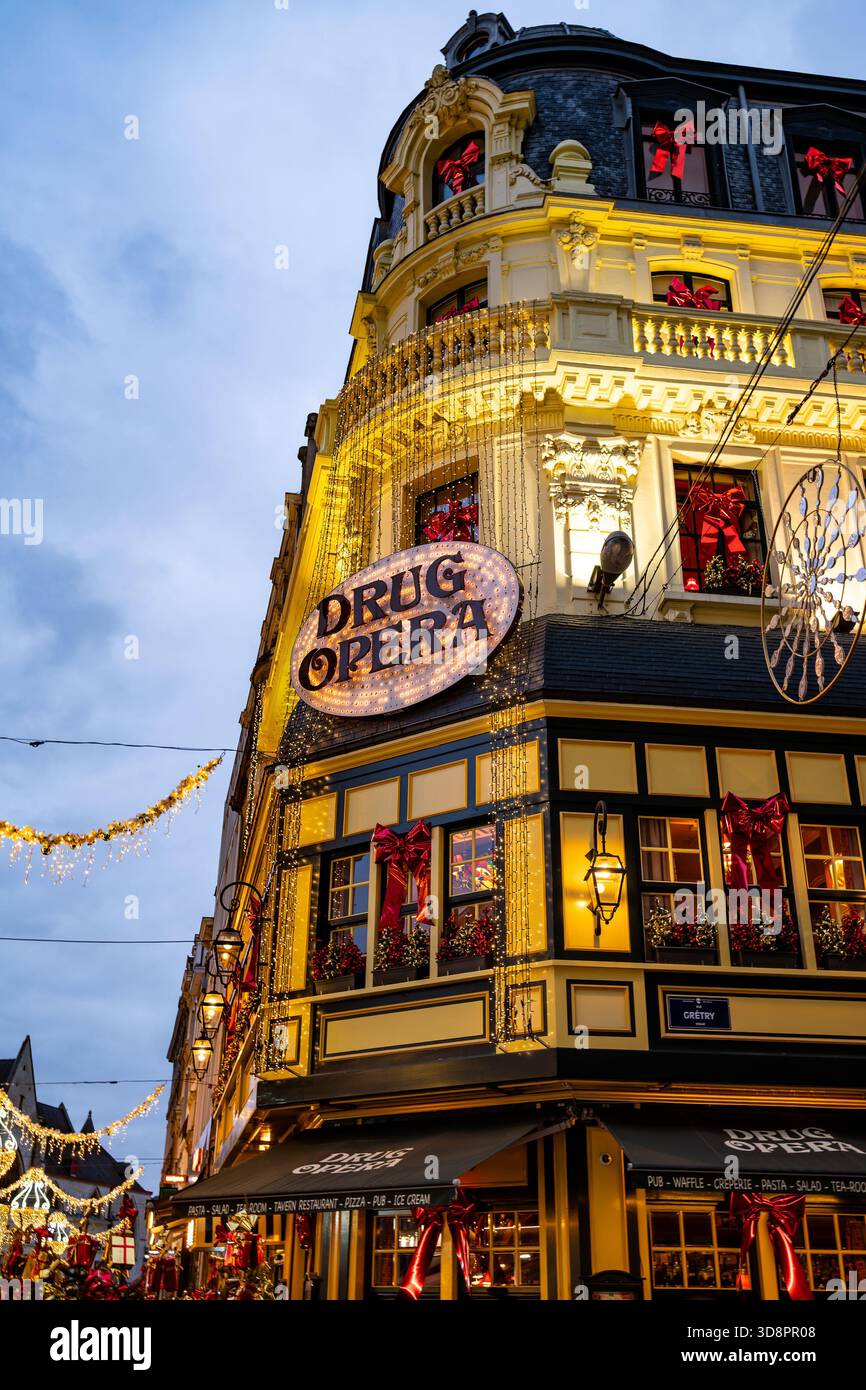 Brüssel, Belgien - 30. November 2025: Das ikonische Gebäude der Drogenoper, beleuchtet mit Weihnachtslichtern und festlichen roten Bändern während der Winterwunder Stockfoto