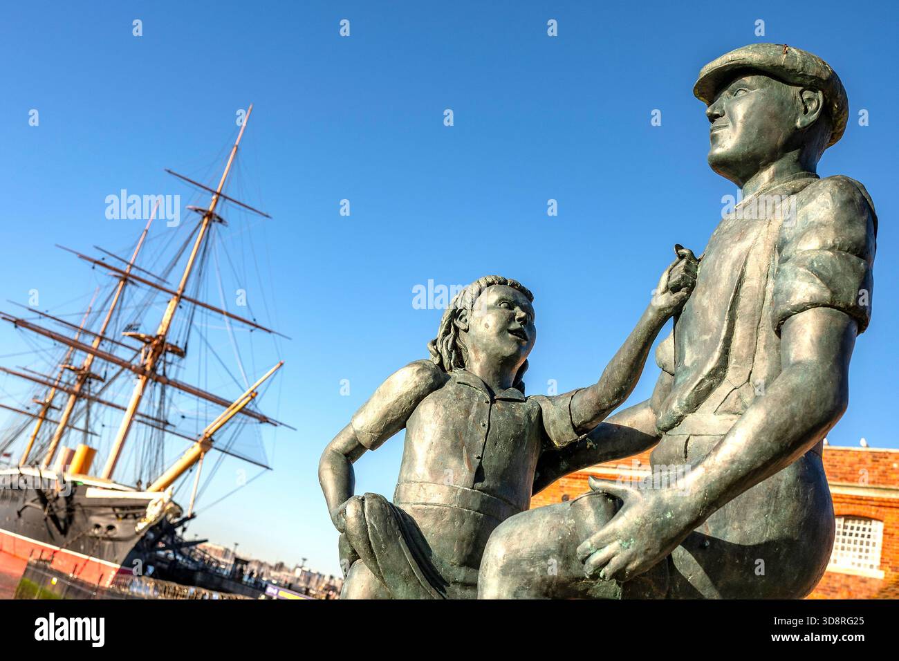 Mudlarks-Gedenkstatue auf dem Hard, Portsmouth Stadtzentrum, Hampshire Großbritannien, mit dem historischen Kriegsschiff HMS Warrior im Hintergrund. Stockfoto