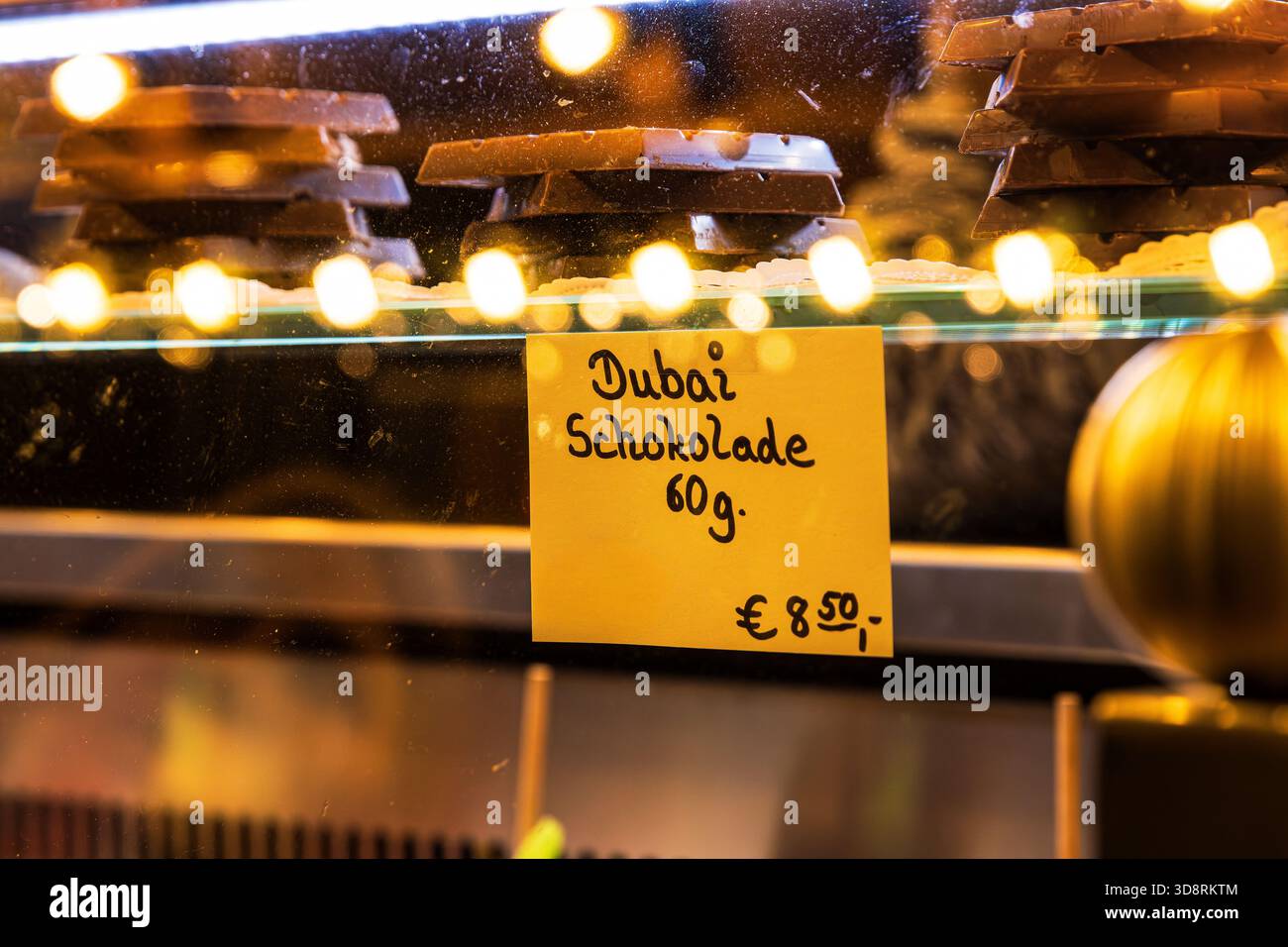 Glasmarktstand mit gestapelten Schokoladenstücken mit handgeschriebenem Schild mit der Aufschrift Dubai schokolade 60 g. Wintermarkt. Weihnachtliche Atmosphäre. Stockfoto