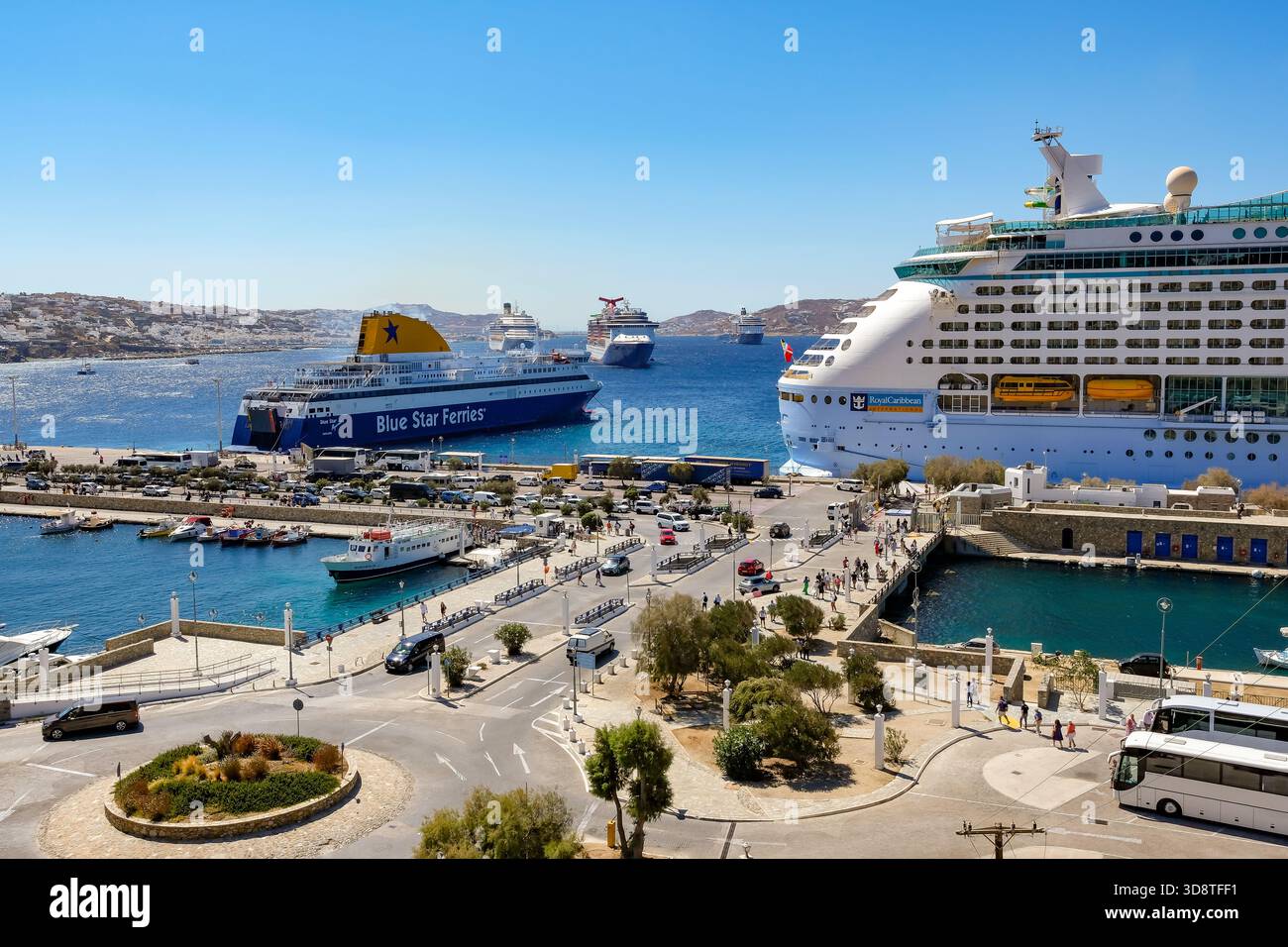 Mykonos, Kykladen, Griechenland - Mykonos New Port, eine Blue Star Ferries Fähre und ein Kreuzfahrtschiff liegen am Kai im neuen Hafen vor dem Skyli Stockfoto