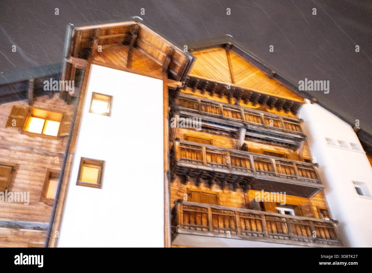 Blick auf hölzerne Wohnhäuser unter Schnee mit Nachtbeleuchtung in Les Gets in Haute-Savoie in Auvergne-Rhone-Alpes in Frankreich am 6. Januar 2024. Die Szene Il Stockfoto