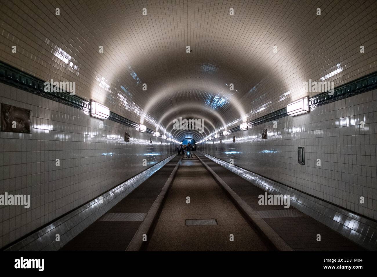 Blick auf Menschen, die im Alten Elbtunnel in Hamburg am 18. Juni 2025 spazieren. Die Szene fängt den historischen Tunnel mit seinen Charakteristika ein Stockfoto