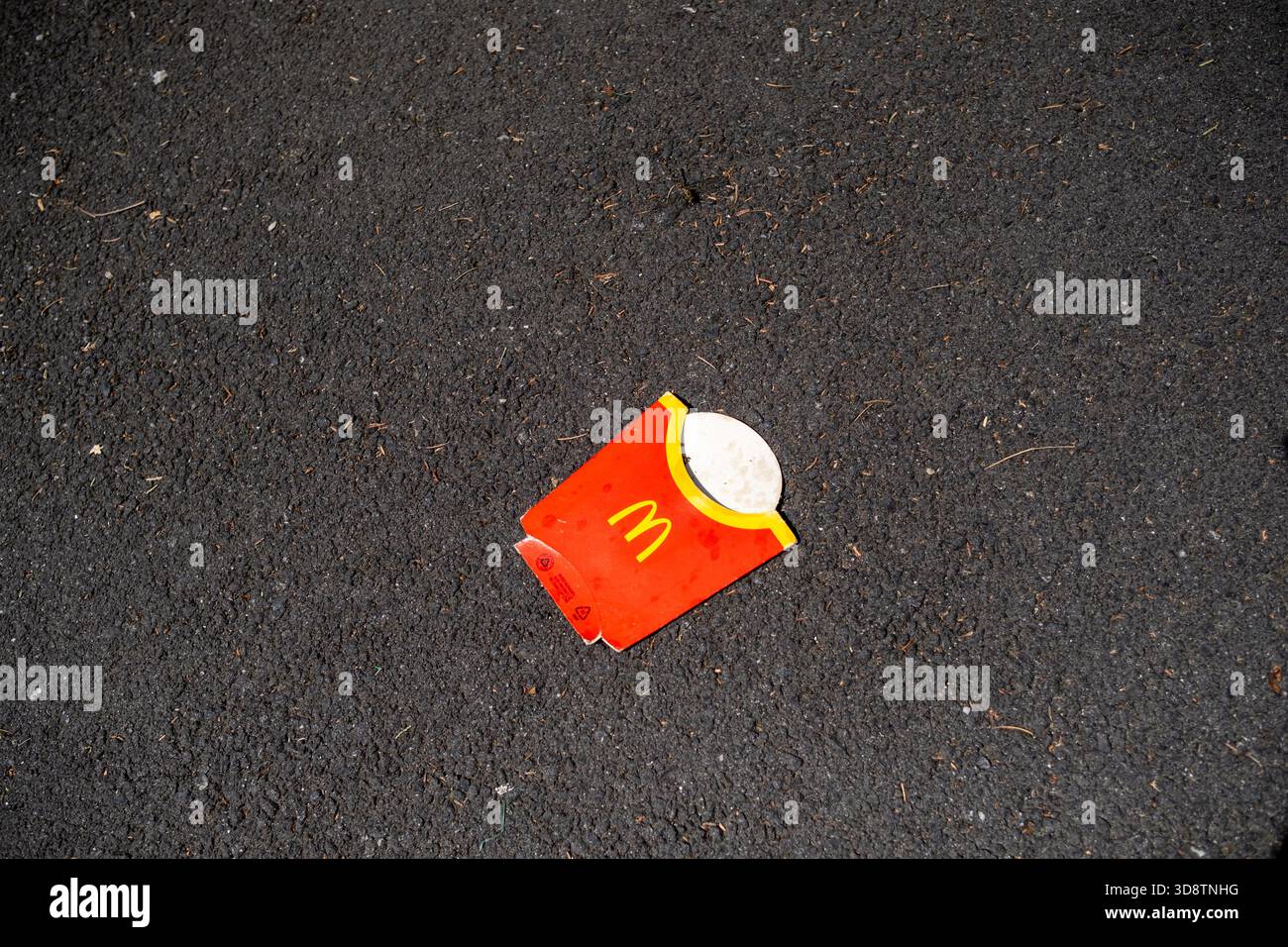 Der McDonalds-Pommes-Container wurde am 2. August 2023 auf der Straße in Toulouse in Occitanie in Frankreich entsorgt. Der Einstreu ist auf dem Asphalt sichtbar, hoch Stockfoto