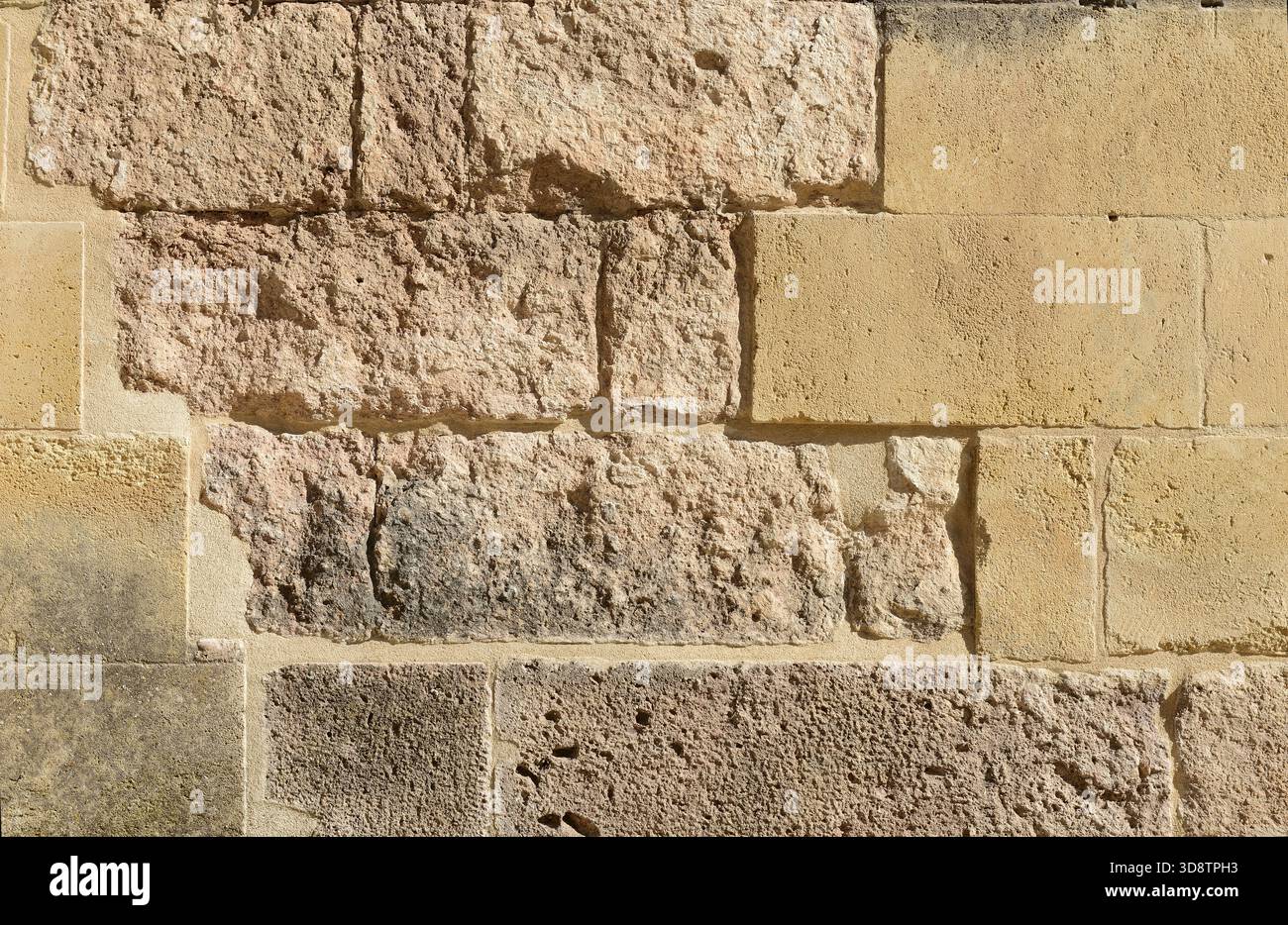 Detaillierte Textur einer hellen Steinwand aus unebenen Blöcken mit ausgeprägter Rauheit. Stockfoto