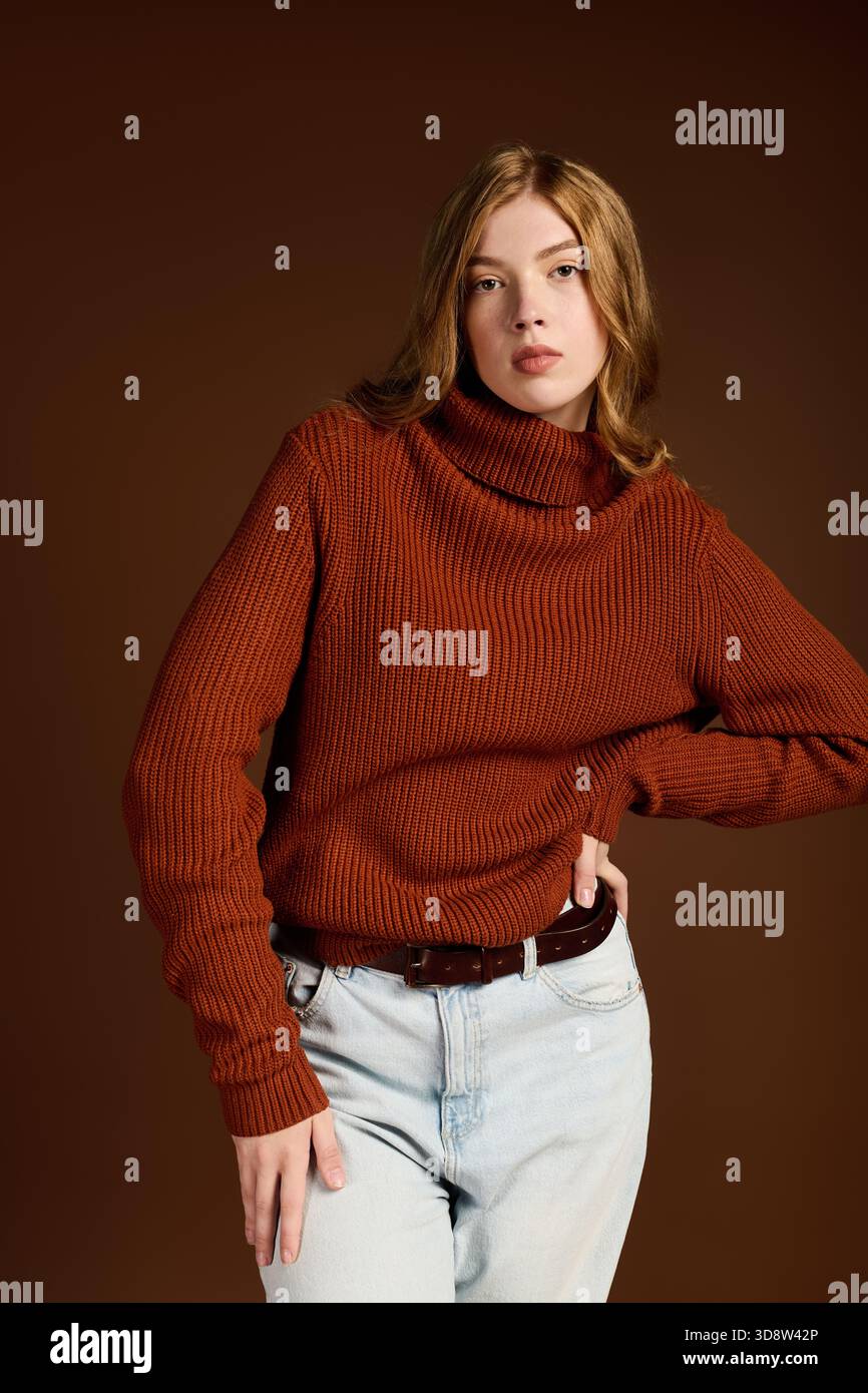 Eine junge rothaarige Frau posiert selbstbewusst in einem gemütlichen Winterpullover. Stockfoto