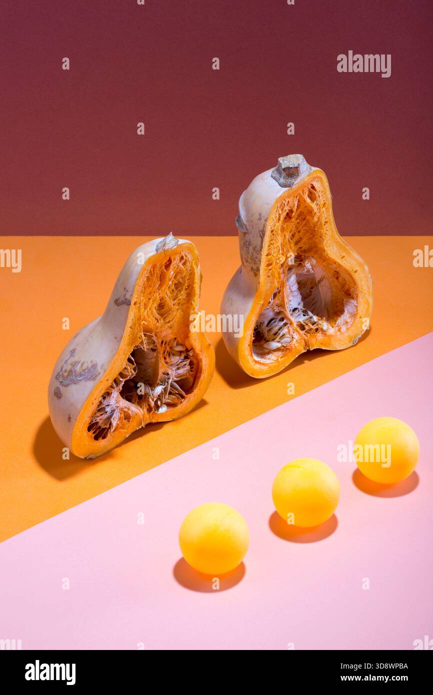 Abstraktes Stillleben mit einem geschnittenen Kürbis und Kugeln auf mehrfarbigem Hintergrund Stockfoto