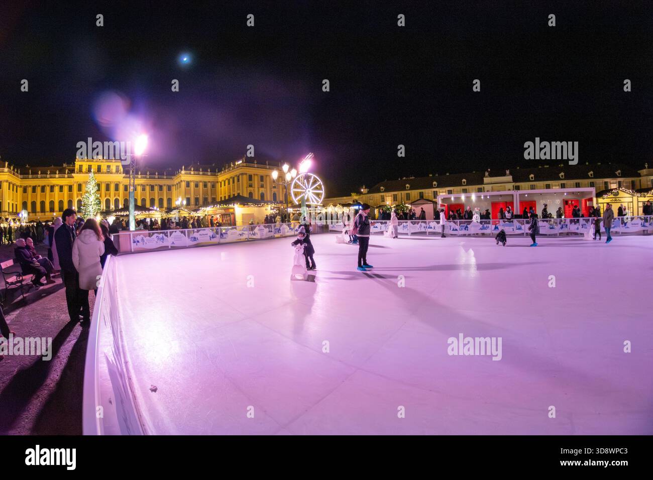 Eislaufbahn und Weihnachtsmarkt vor dem beleuchteten Schloss Schönbrunn in Wien, Österreich. Stockfoto