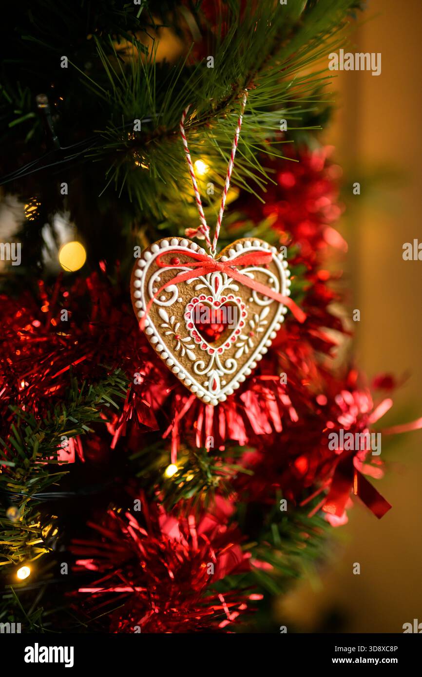 Ein handgefertigtes Lebkuchenschmuck hängt an einem Weihnachtsbaum, beleuchtet von einem warmen, festlichen Leuchten. Ein gemütliches, hochwertiges Bild für den kommerziellen Urlaub Stockfoto