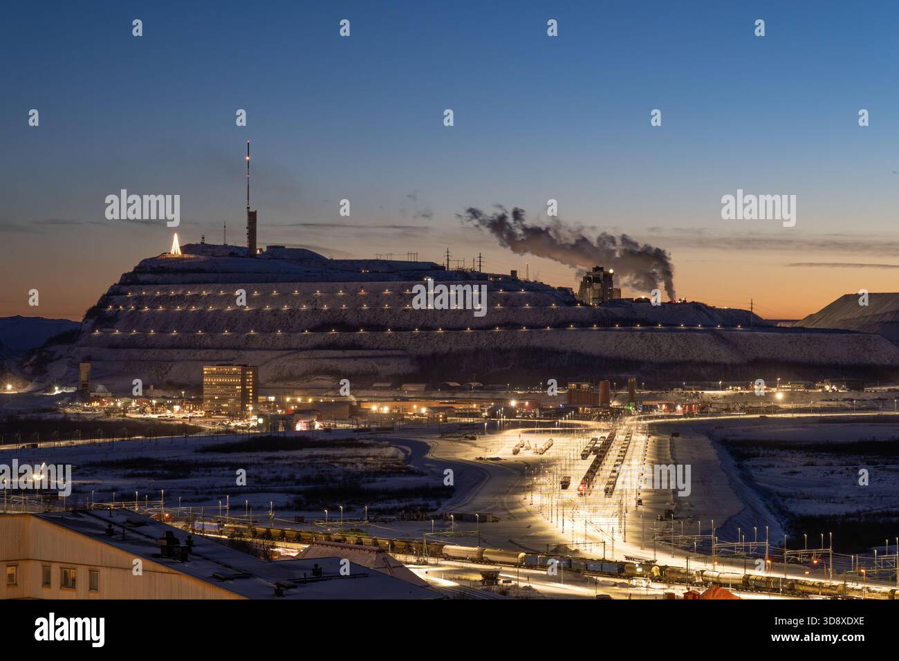 Eisenerzmine in Kiruna, Schweden, während der Polarnacht im Winter, mit Zügen, die auf Eisenerz und Industriegebäude warten Stockfoto