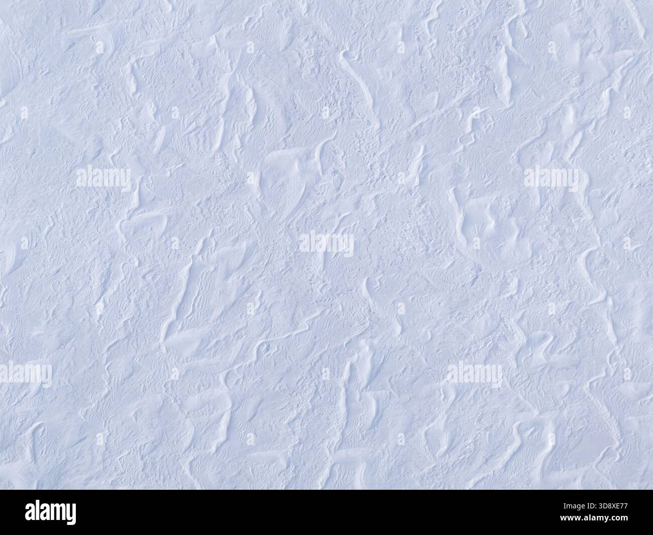 Gefrorener See, bedeckt mit Schnee, Muster und Texturen von treibendem Schnee, die Schatten auf einem See erzeugen Stockfoto