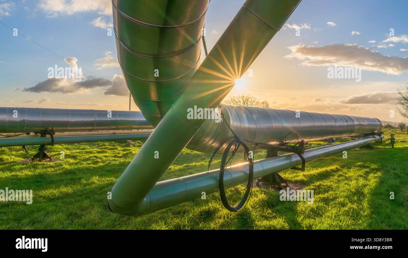 Blick auf große industrielle Pipelines, geothermische Energie, durch ein grünes Feld in der Landschaft in der Nähe von Larderello, Pomarance, Provinz Pisa, Tusca Stockfoto
