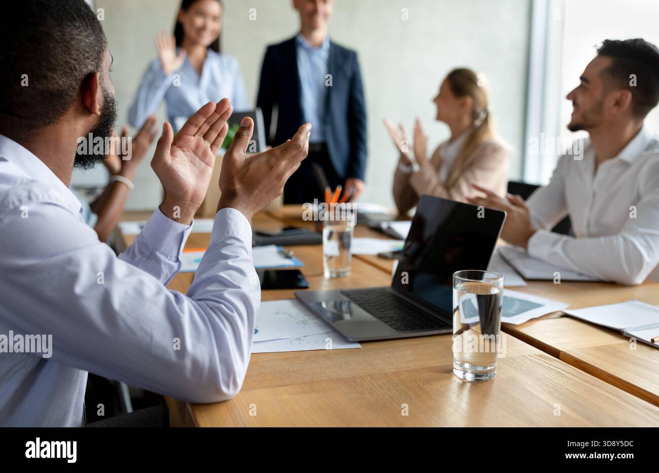 Eine Gruppe von Kollegen begrüßt das neue Teammitglied während der Besprechung im Konferenzraum des Büros Stockfoto