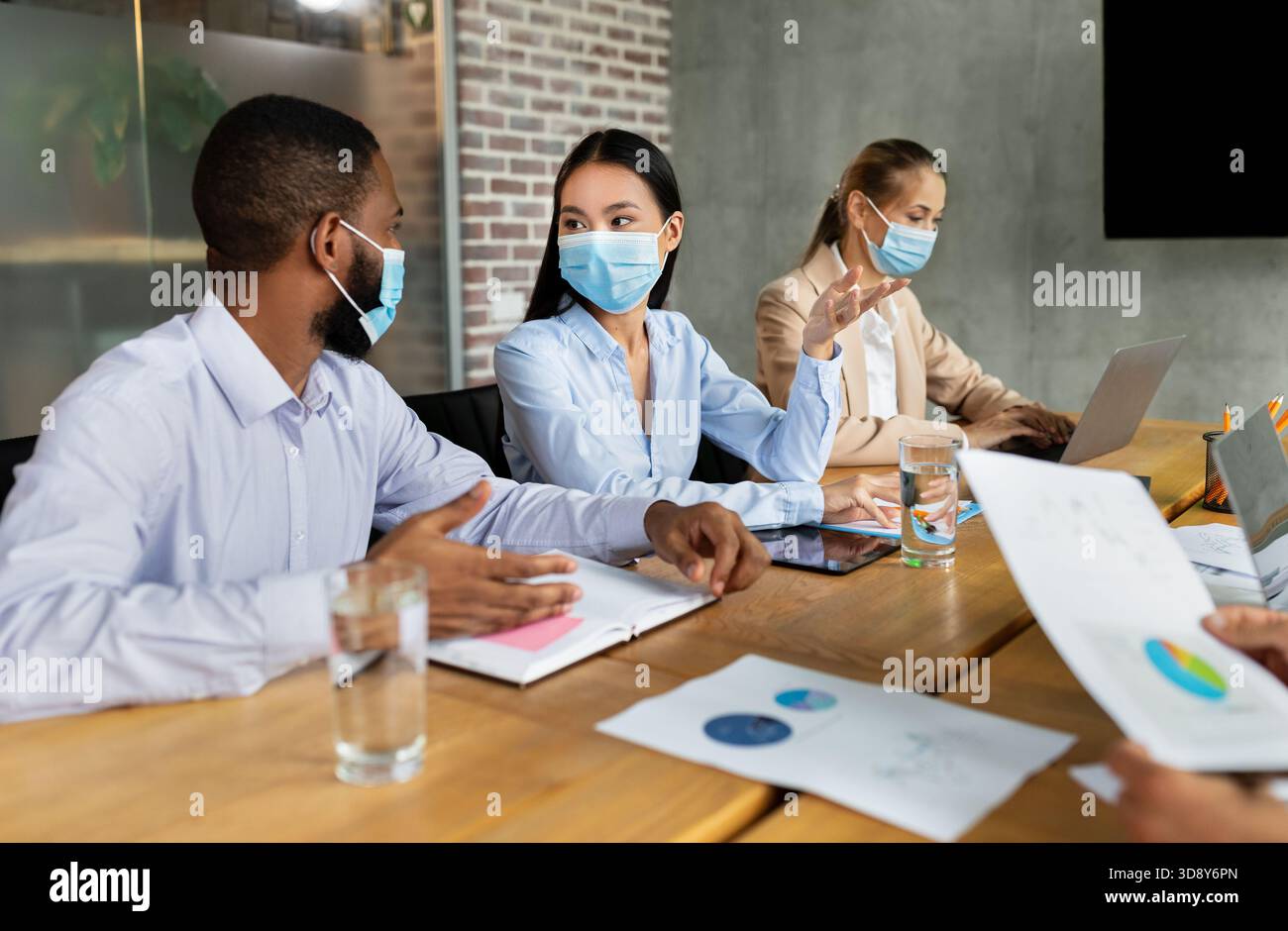 Während der Pandemie arbeiten verschiedene Geschäftsleute in einem Konferenzraum zusammen Stockfoto