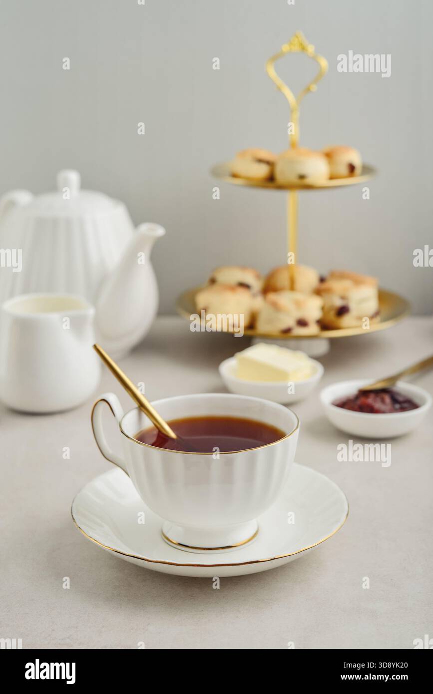 Englischer Nachmittagstee in eleganten weißen Porzellantassen serviert mit Scones, Milch, Butter und Marmelade, fünf O'Clock-Tee Stockfoto