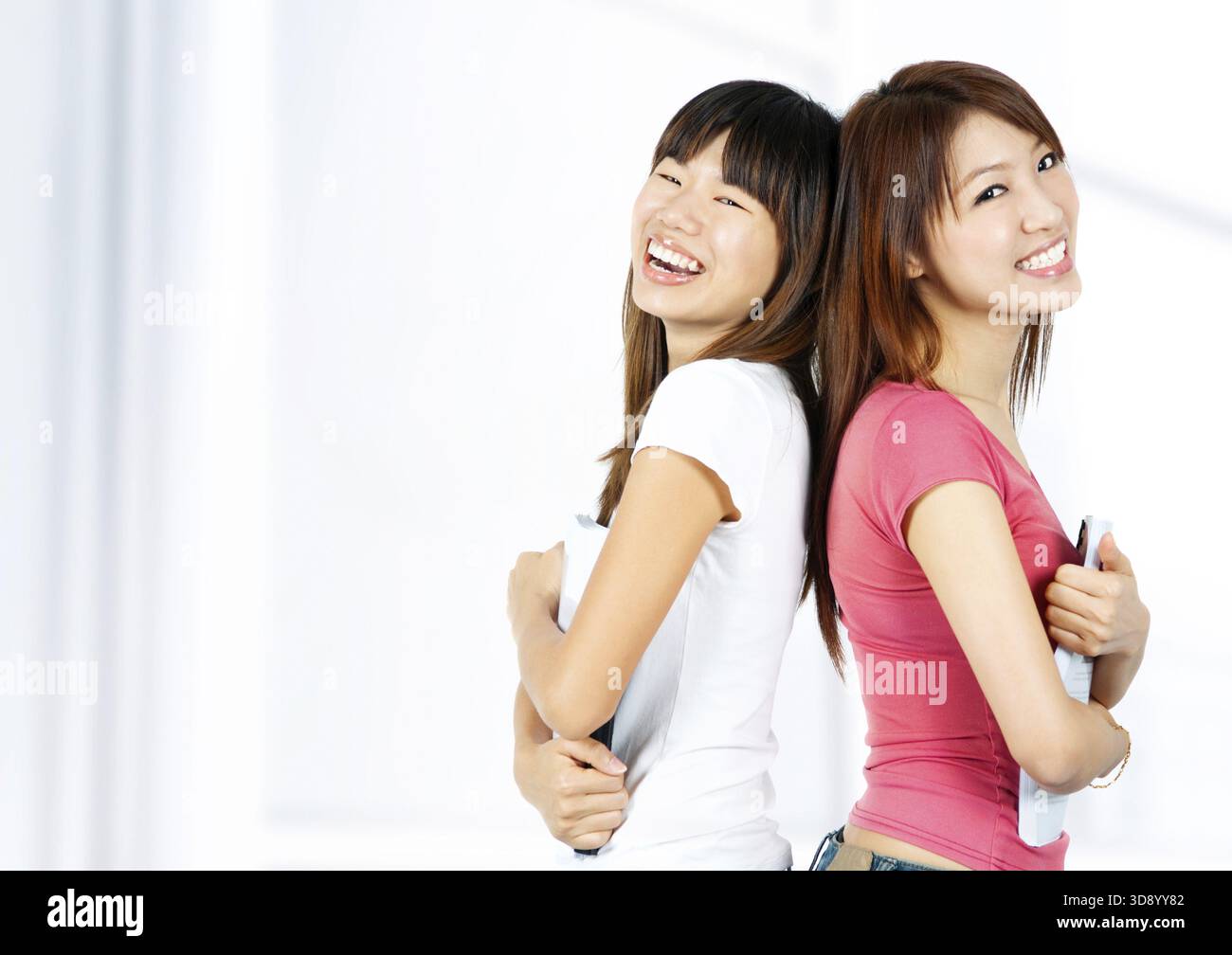 Glückliche asiatische Schüler mit Büchern auf dem Schulgelände Stockfoto