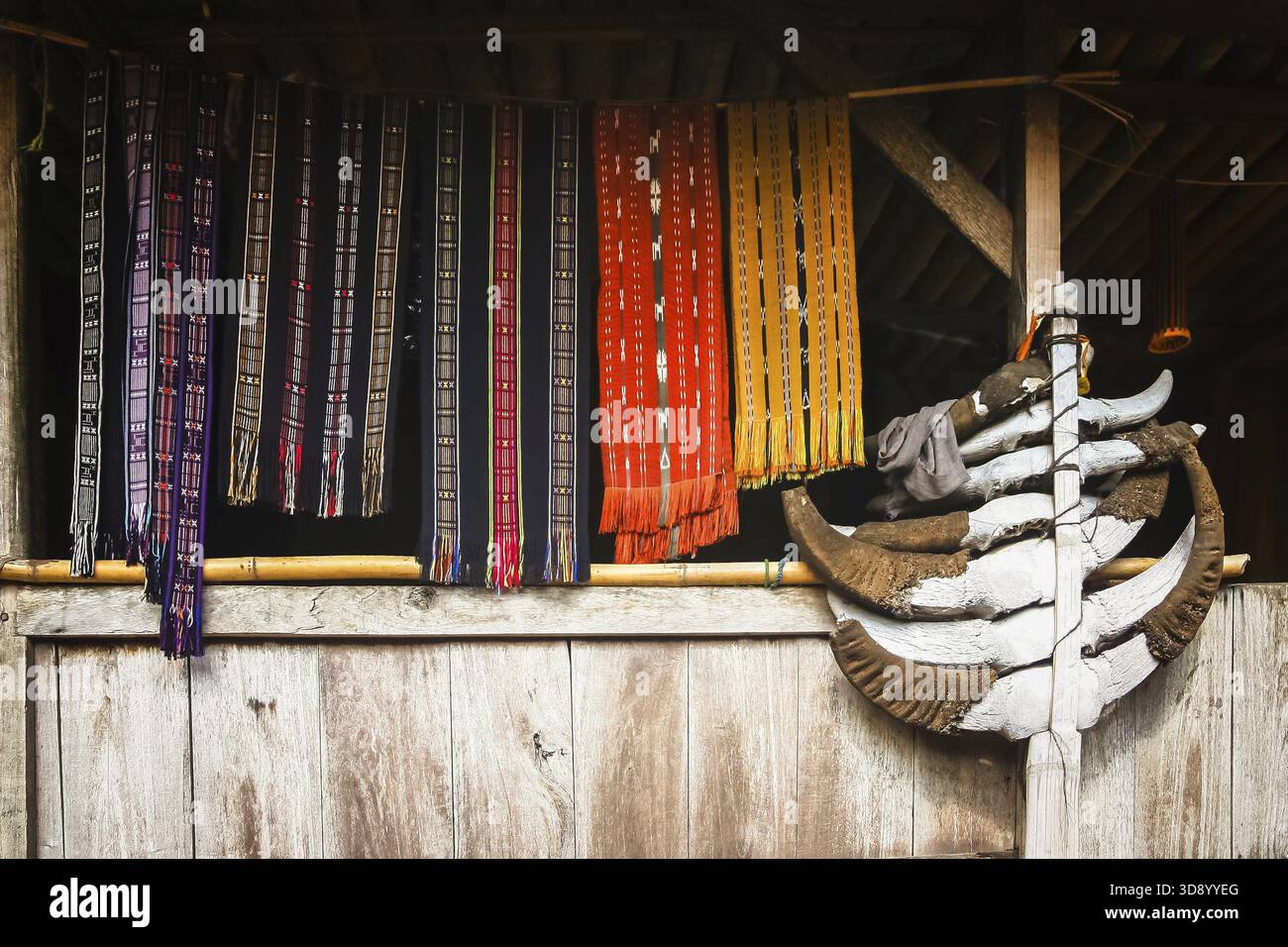 Bunte Kleidung Zubehör und Schals erhängt an einem Bambusstab im Fenster des traditionellen Hütte im Dorf Bena auf Flores Island zu trocken, ICH Stockfoto