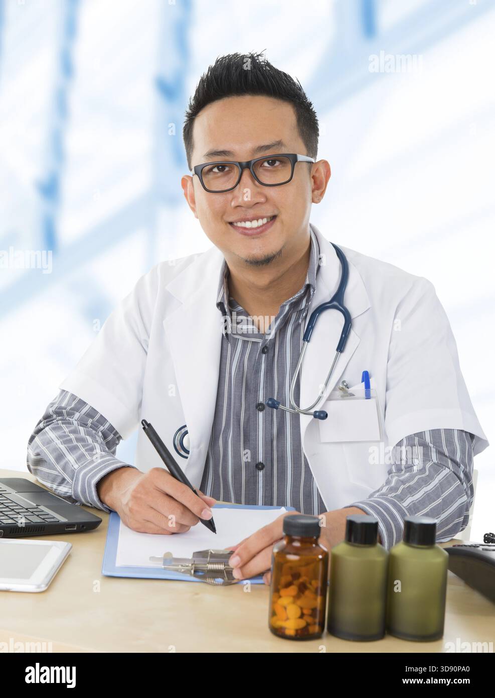 Junger südostasiatischer Arzt, der auf seinem Schreibtisch im Krankenhauszimmer arbeitet Stockfoto