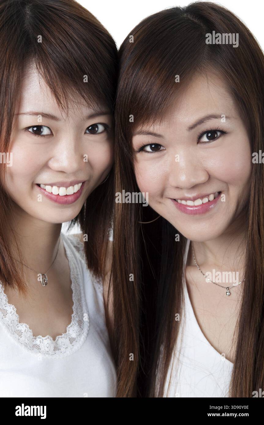 Schließen Sie sich fröhlich asiatische Mädchen auf weißem Hintergrund Stockfoto