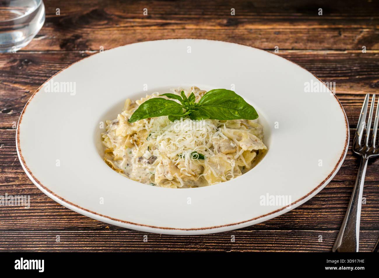 Cremige Pilznudeln mit geriebenem Parmesan und frischem Basilikum Stockfoto