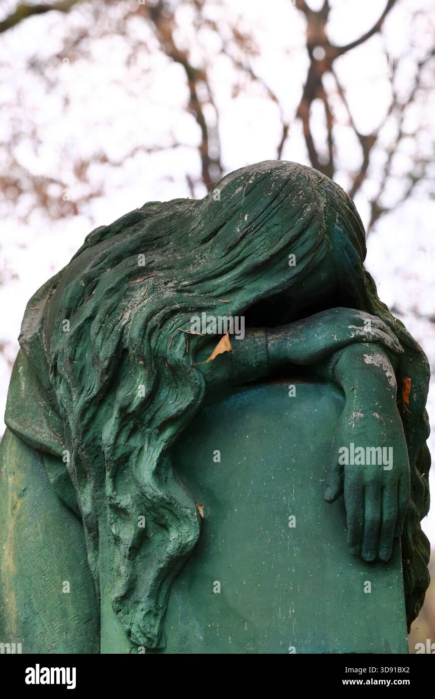 Moosbedeckte Trauerstatue auf einem düsteren Friedhof im Herbst Stockfoto