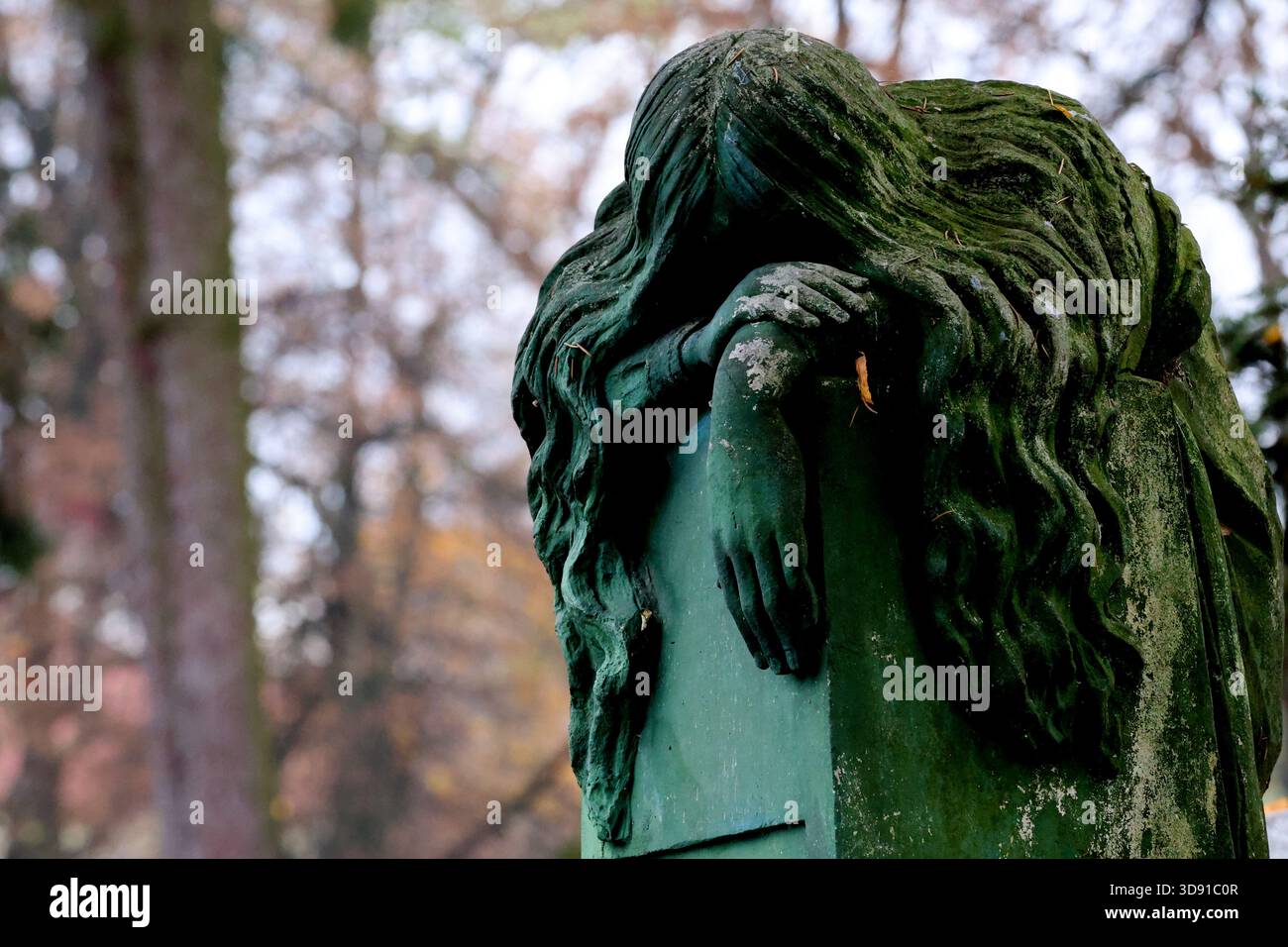 Moosbedeckte Trauerstatue auf einem düsteren Friedhof im Herbst Stockfoto