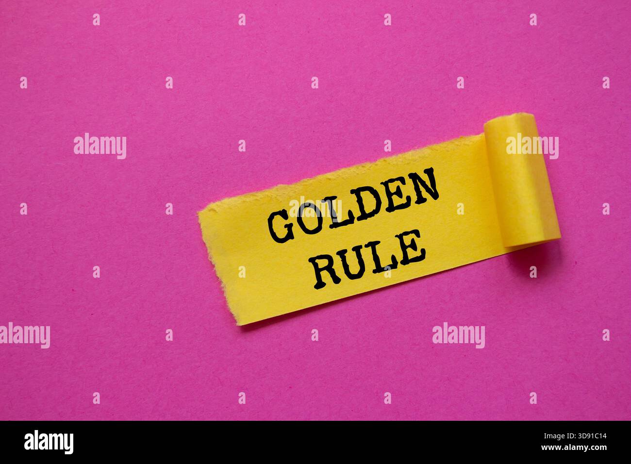 Goldene Regelnachricht auf gerissenem gelbem Papierstück auf rosa Hintergrund. Konzeptionelles goldenes Regelsymbol. Kopierbereich. Stockfoto