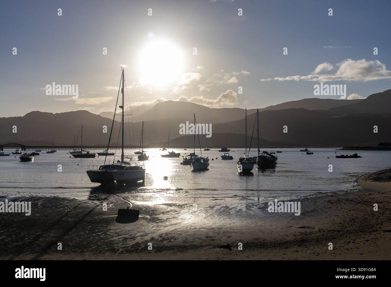 Boote bei Ebbe mit starkem Sonnenlicht über dem Hafen von Barmouth Stockfoto
