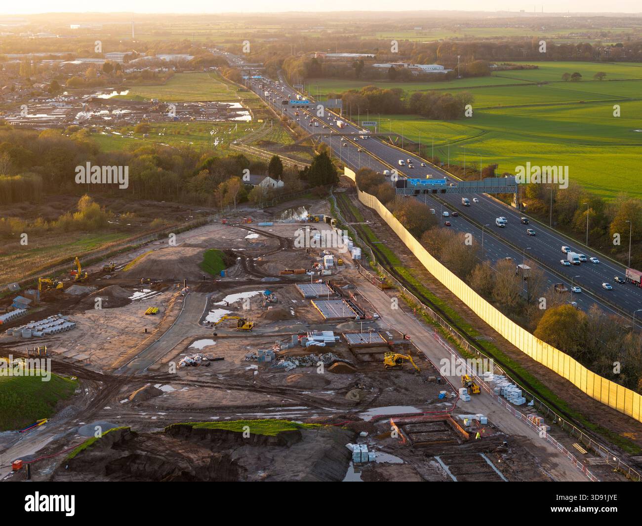 WARRINGTON, CHESHIRE, ENGLAND – 17. NOVEMBER 2025: Wohngebäude mit einer akustischen Barriere entlang der Autobahn M62 in Warrington, England. Stockfoto