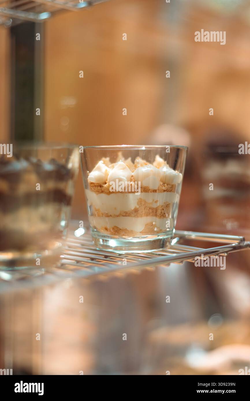 Elegante Nahaufnahme eines mehrschichtigen Napoleons (Mille-feuille), serviert in einem Glas – cremiger Pudding, knuspriger Blätterteig und Puderzucker. Stockfoto