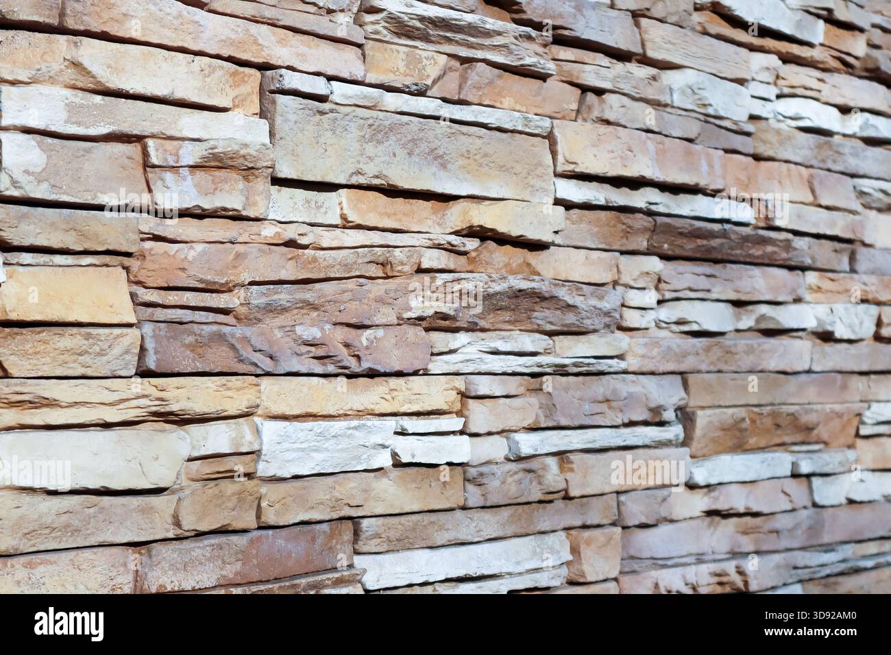 Detaillierte Ansicht einer Natursteinmauer mit gestapelten beigen und braunen Blöcken, die unregelmäßige Formen und strukturierte Oberflächen in Erdtönen hervorheben. Stockfoto