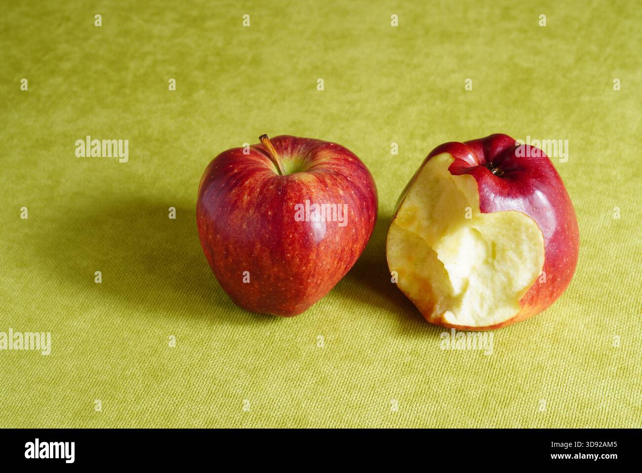 Großaufnahme von ganzen und gebissenen Starkrimson roten Äpfeln auf grünem Hintergrund mit Kopierraum Stockfoto
