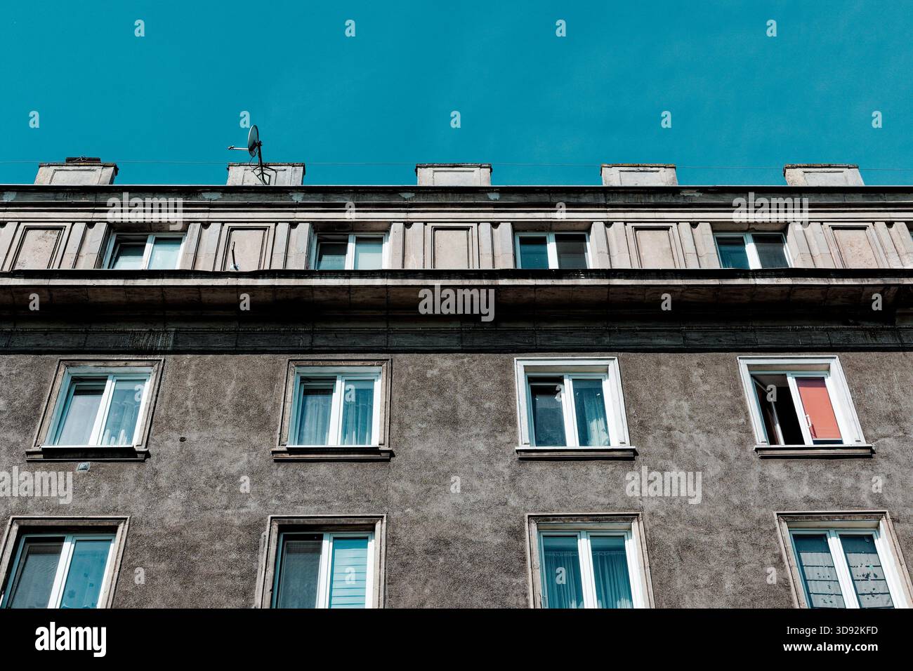 Obere Stockwerke und Dachterrasse eines Wohnhauses mit sozialistischem Realismus unter blauem Himmel in Nowa Huta. Stockfoto