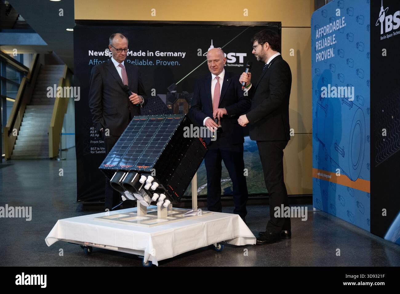 Berlin, Deutschland. Dezember 2025. Bundeskanzler Friedrich Merz (CDU, l-r) und Kai Wegner (CDU), Regierender Bürgermeister von Berlin, sprechen mit Tom Segert, Geschäftsführer von Berlin Space Technologies, während eines Besuchs bei der Firma Berlin Space Technologies. Quelle: Christophe Gateau/dpa/Alamy Live News Stockfoto