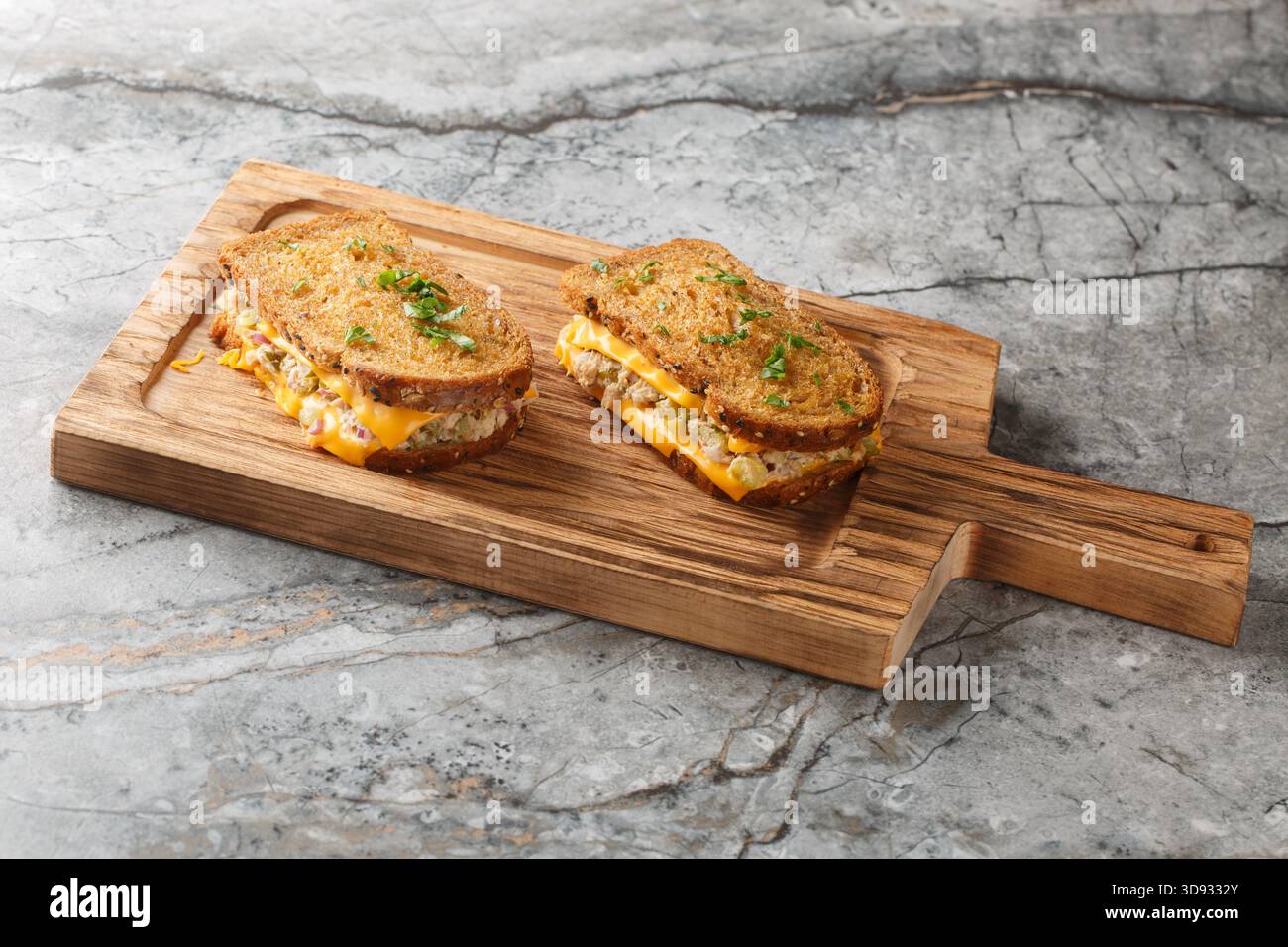 Köstliche frische Thunfischschschmelze-Toasts aus Roggenbrot, Thunfisch aus Dosen mit Gemüse und Mayonnaise und geschmolzenem Käse in Nahaufnahme auf einem Holzbrett auf dem t Stockfoto