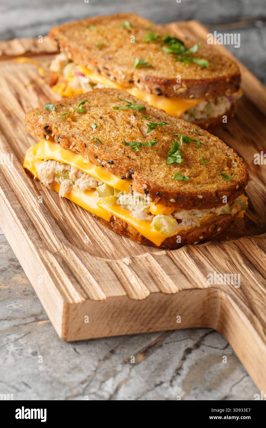 Klassisches Thunfischschschmelzsandwich mit Käse auf Butterbrot aus Roggenbrot auf Holzbrett auf dem Tisch. Vertikal Stockfoto