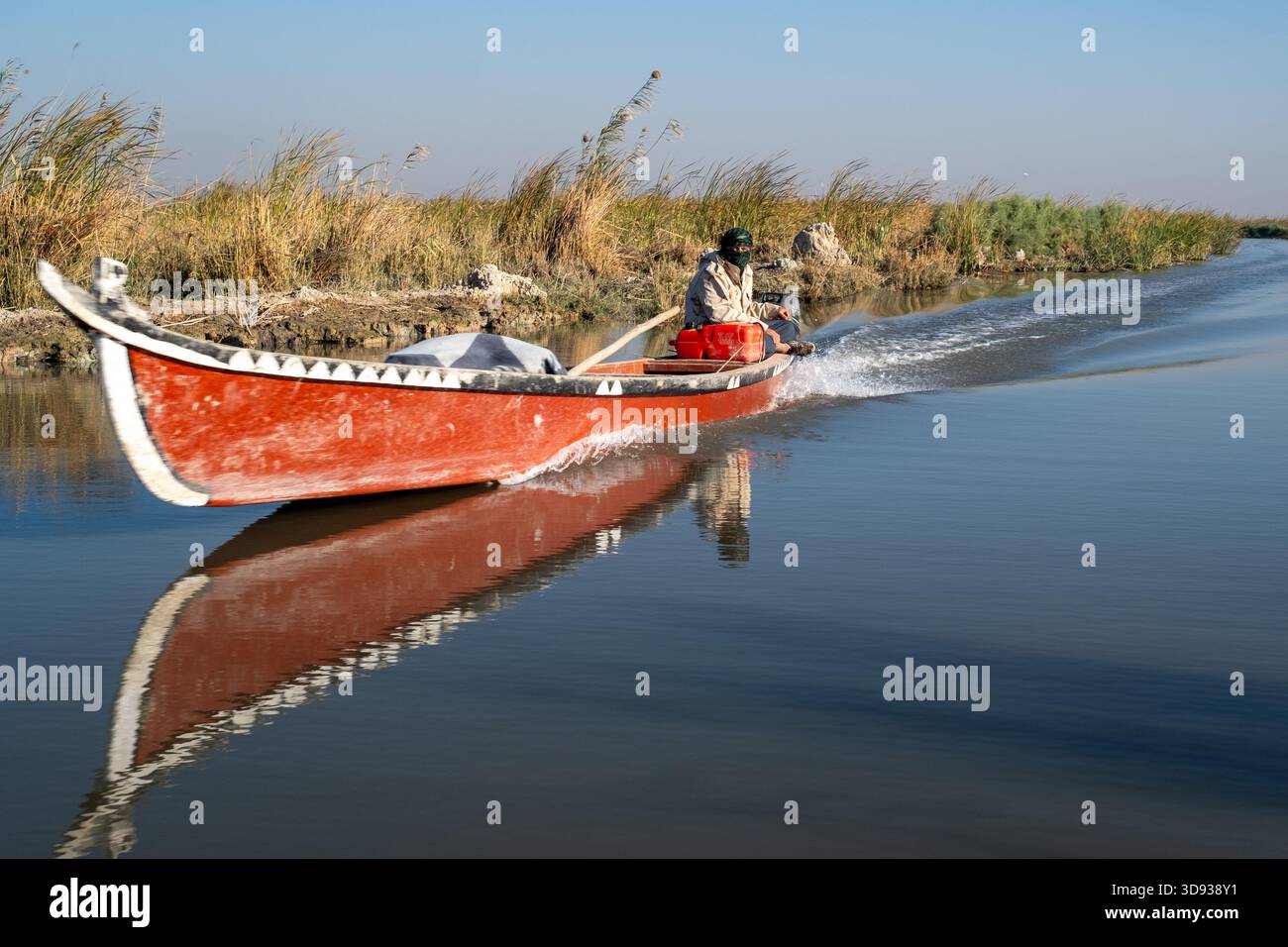 Traditionelles rotes Mashhouf-Boot, das durch die ruhigen Chibayish-Sümpfe fährt Stockfoto