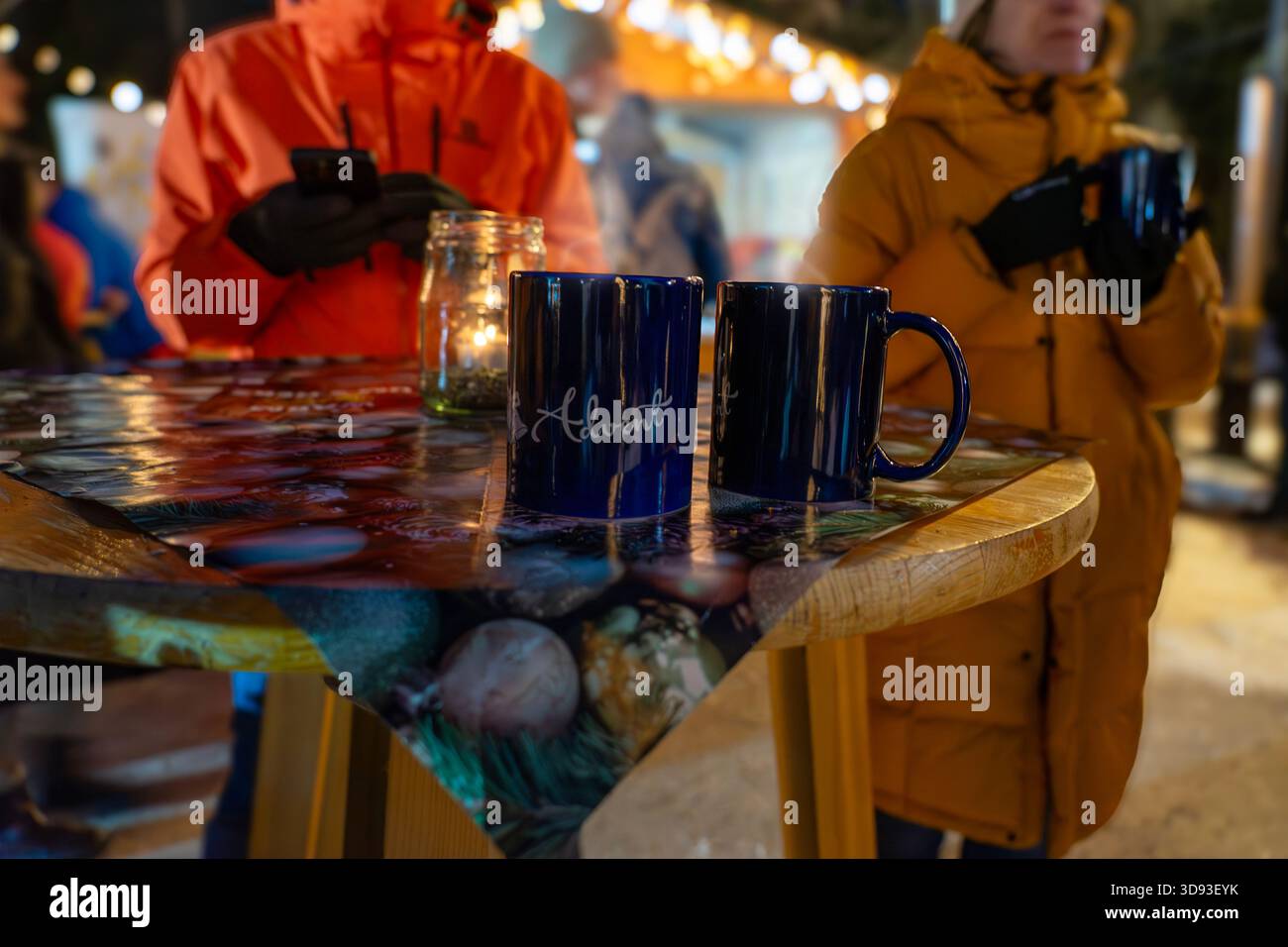 Zwei Tassen auf einem festlichen Tisch auf einem Wintermarkt mit warmem Licht und Kerzen Stockfoto