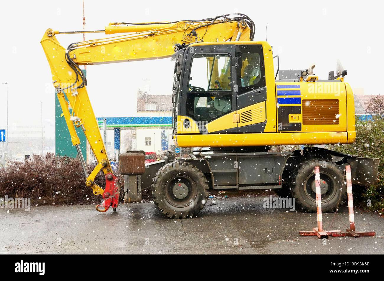 Gelber Bagger auf einer Baustelle bei Schneefall im Winter Stockfoto