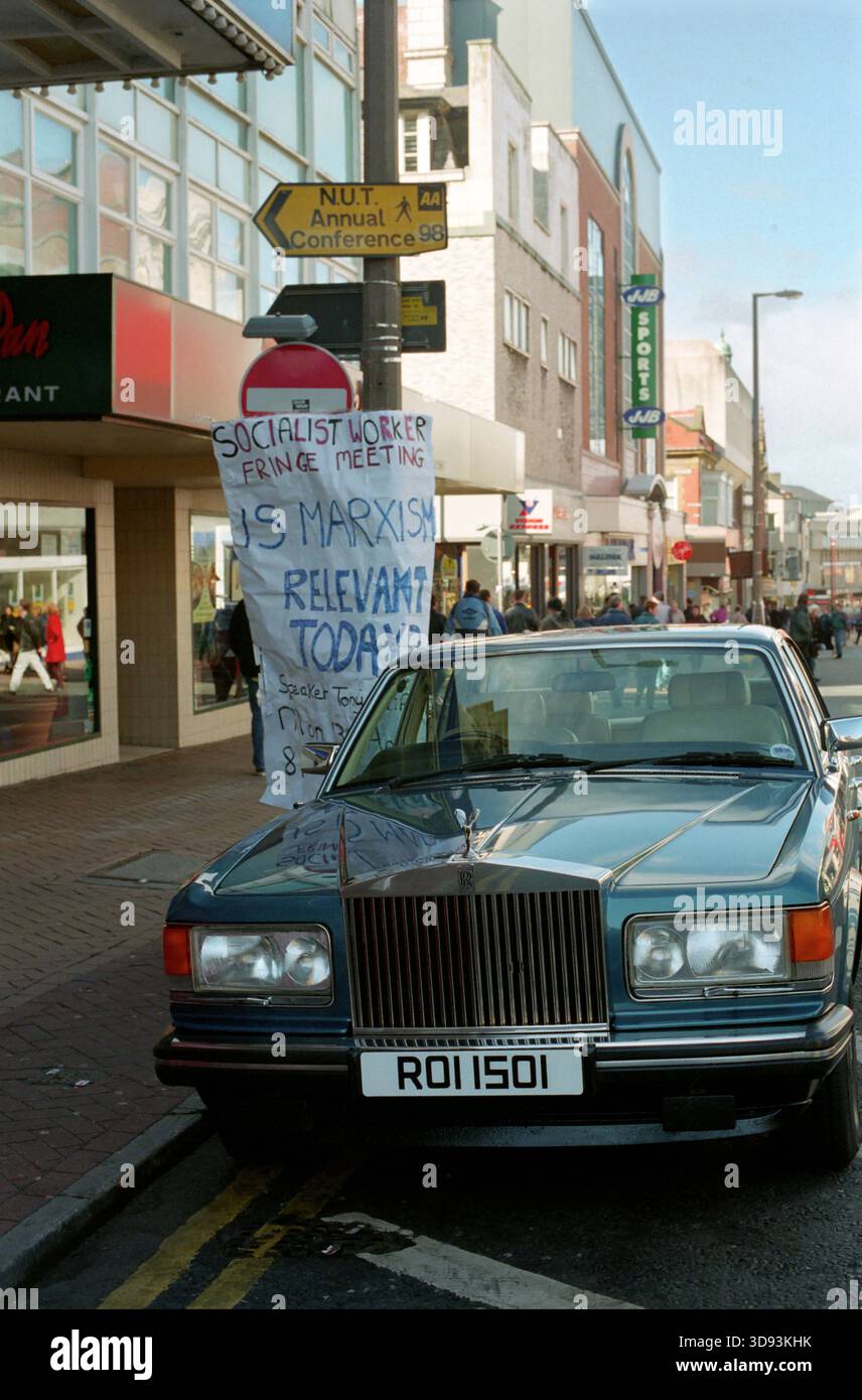 Ein Rolls Royce parkte unter einem Schild, das einen Vortrag über den Marxismus und ein Schild für eine Lehrkonferenz in Blackpool warb. Stockfoto