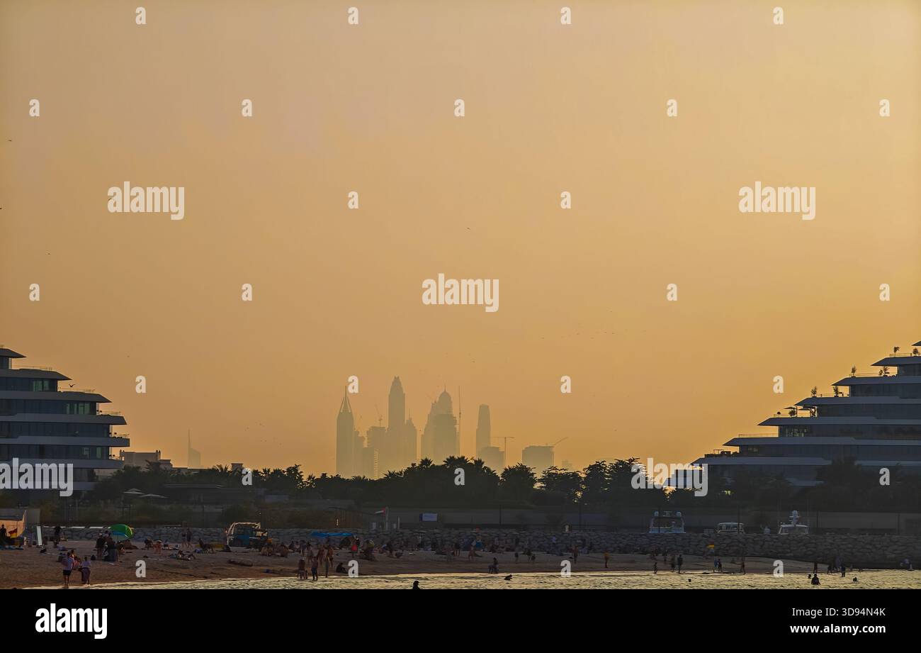 Skyline von Dubai Marina bei Sonnenuntergang vom Jumeirah Beach mit leuchtenden Stadtsilhouetten. Blick auf die Golden Hour Stockfoto