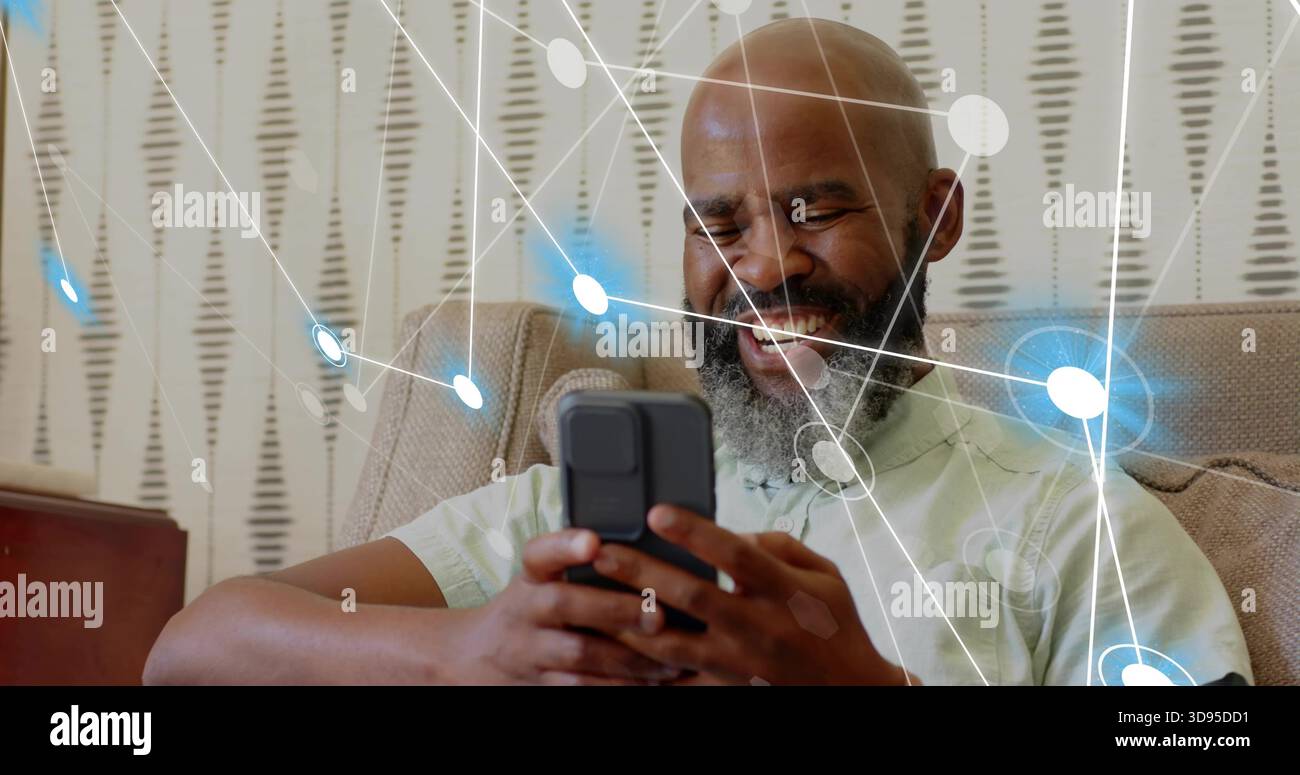 Lächelnder Mann in grünem Hemd, der Smartphone hält, zu Hause auf beigefarbenem Sofa surft, Netzwerk-Overlays Stockfoto