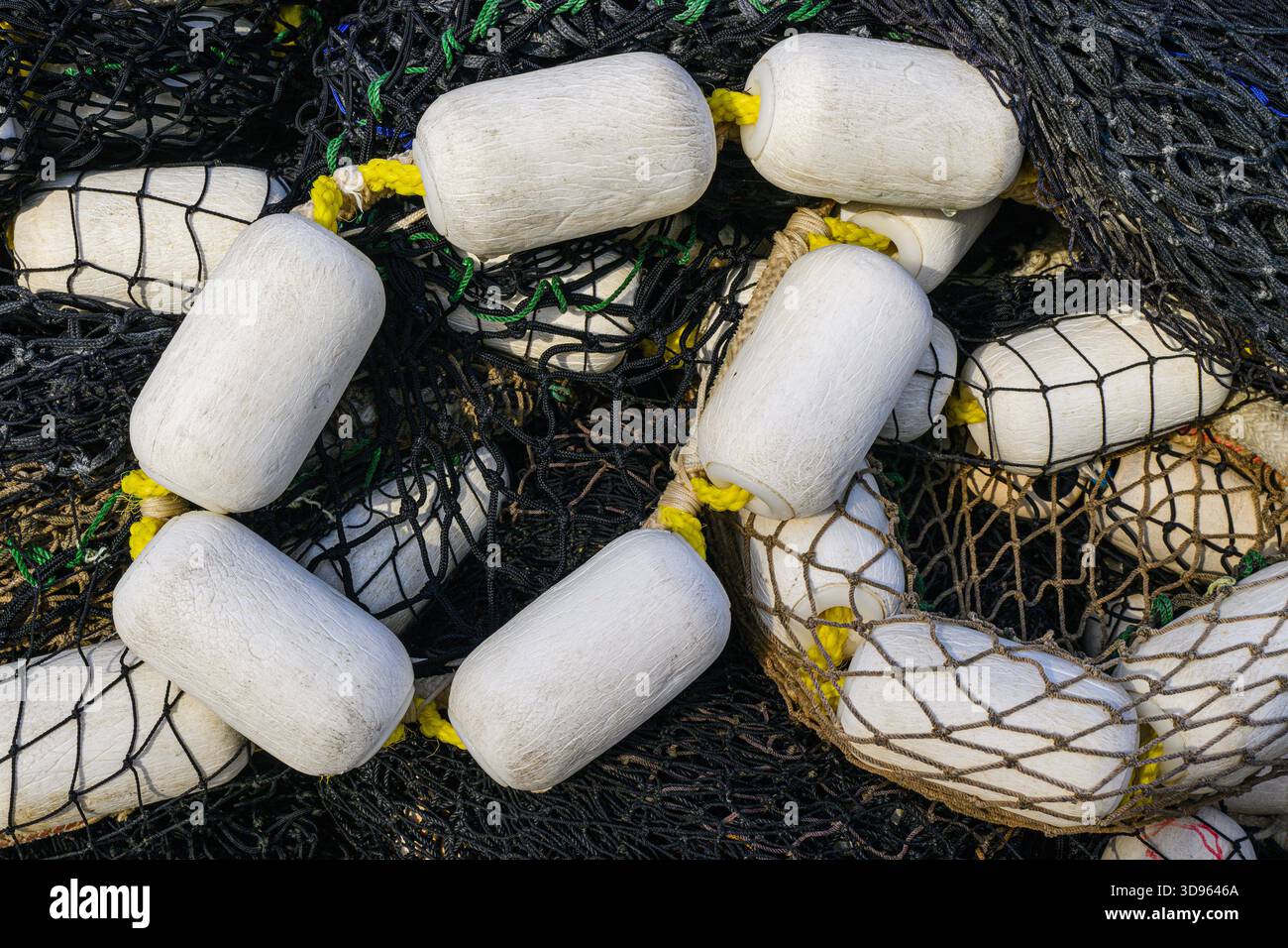 Schwarzes industrielles Fischernetz und weiße Schwimmer in der Nähe bilden ein fließendes Muster Stockfoto