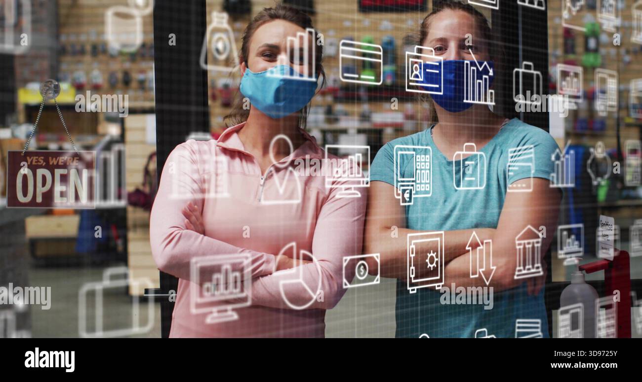 Frauen im mittleren Erwachsenenalter mit Masken, lange Oberteile hinter einem Glasladen mit Techniksymbolen, OFFENEM Schild, Pumpe Stockfoto