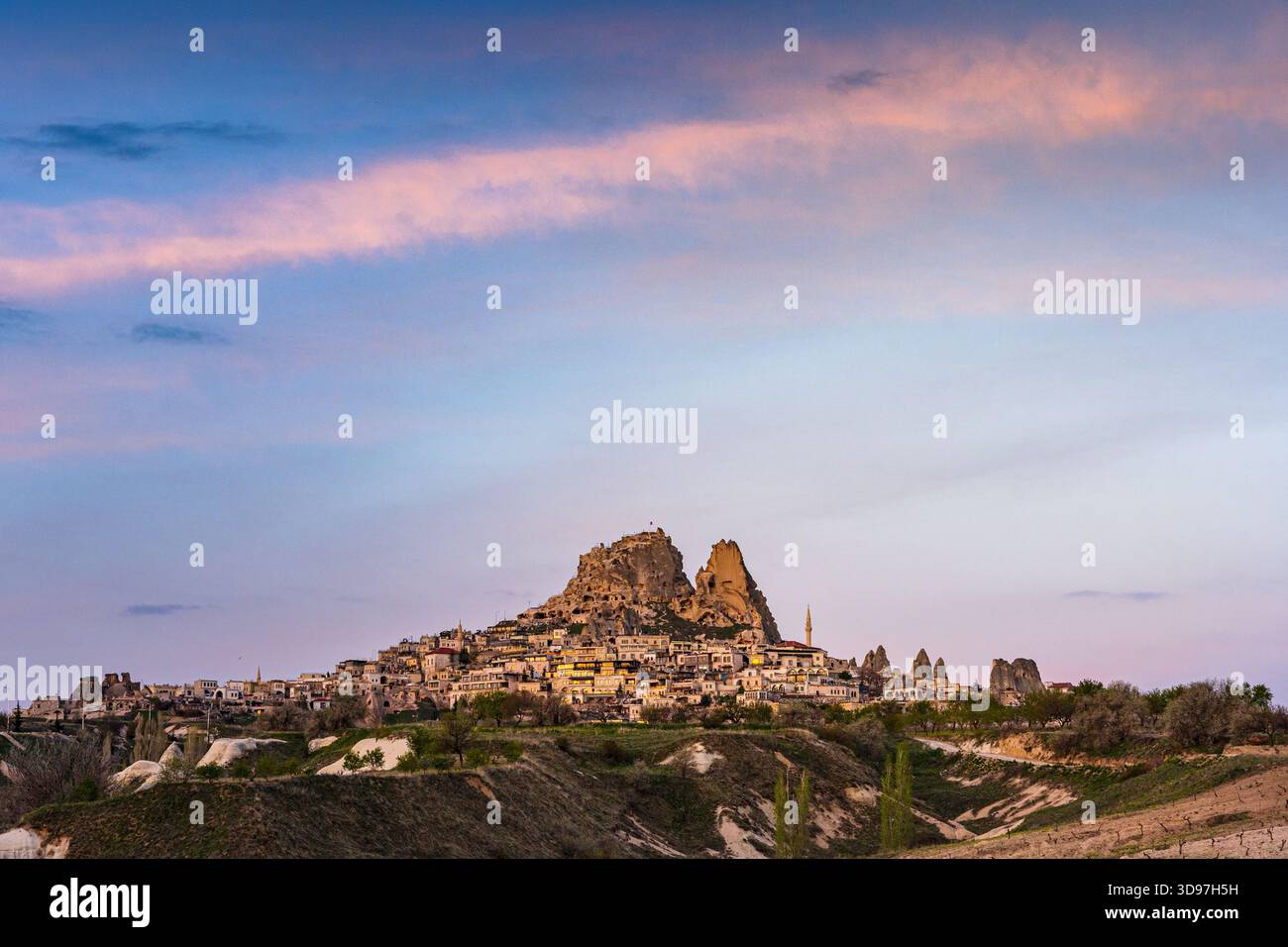Aus der Vogelperspektive der alten Felsformationen und Wohnungen der Burg Uchisar leuchten unter den sanften, pastellfarbenen Tönen des Abendhimmels, Goreme, Kappadokien, T Stockfoto