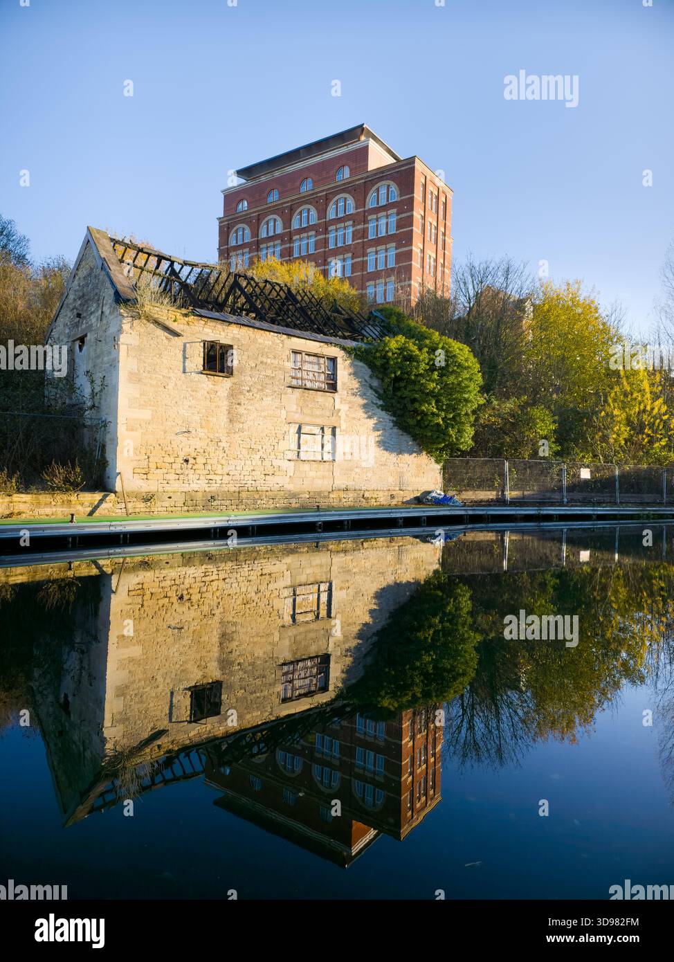 Verlassene Steinhütte und Red-Brick Mill Reflection on Calm Canal – Herbst Cotswolds England UK Stockfoto